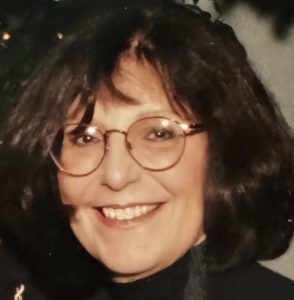 Headshot of smiling white woman with shoulder-length dark hair wearing glasses